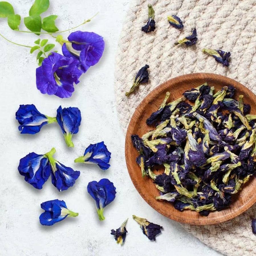 Butterfly pea powder beside the tin on a wood slice